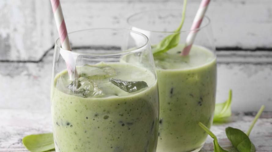 2 Gläser mit grünem Smoothie, Eiswürfeln und Strohhalm