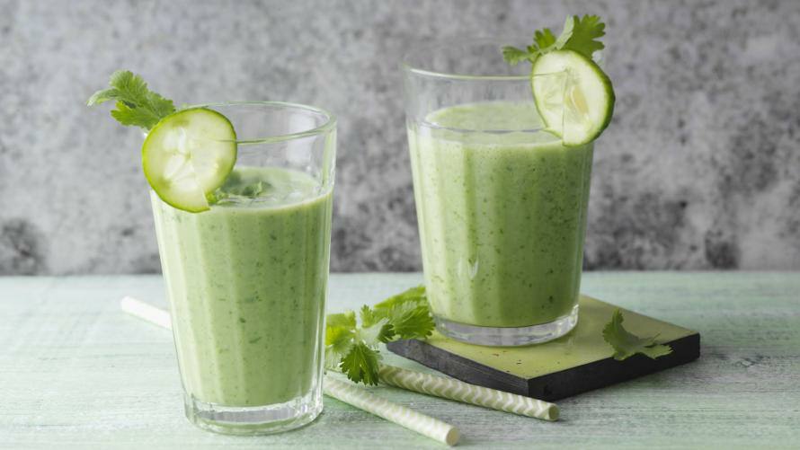 2 Gläser mit grünem Smoothie, garniert mit Gurkenscheibe und Koriandergrün