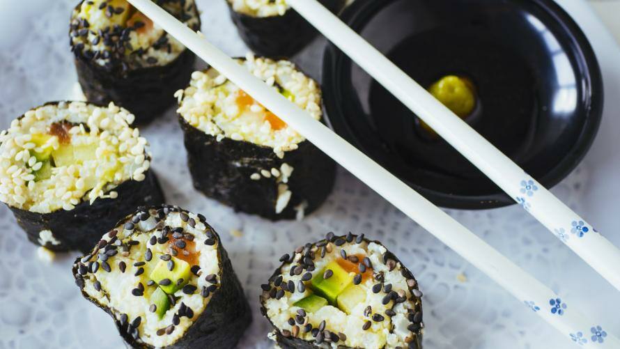 Sushi mit Blumenkohlreis auf einem Teller mit Stäbchen und Sojasauce