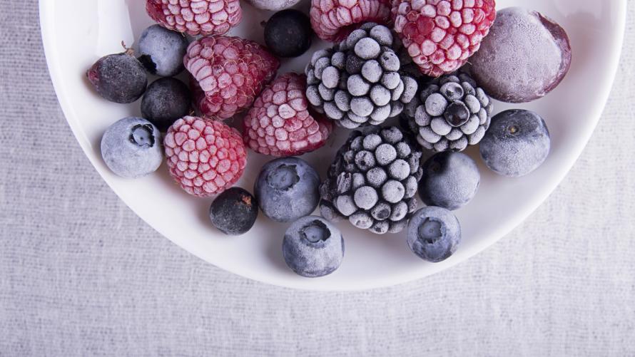 Gefrorene Beeren (Himbeeren, Brombeeren, Blaubeeren) auf weißem Teller