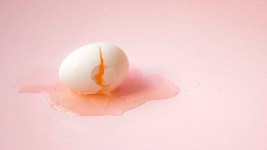 Aufgeschlagenes Ei auf rosanem Untergrund