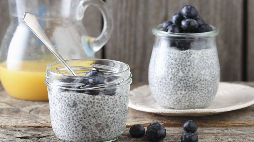 Chia-Pudding in Glas mit Beeren und Kanne mit O-Saft