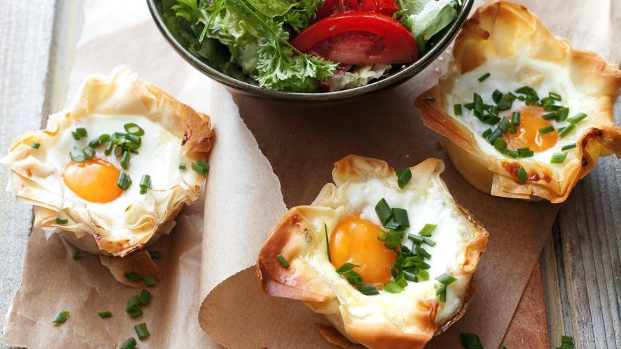 Törtchen aus eiern auf einem Tisch, danaben bunter Salat