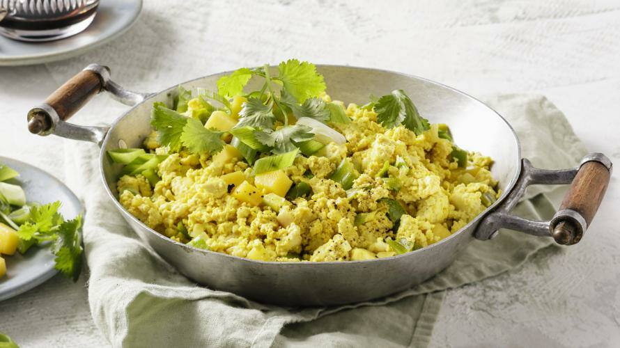 Veganes Tofu-'Rührei' mit Mango in einer schwarzen Pfanne.