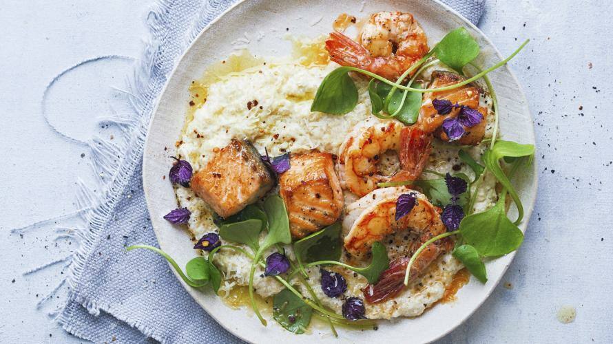 Blumenkohlreis mit Lachs und Garnelen auf einem Teller