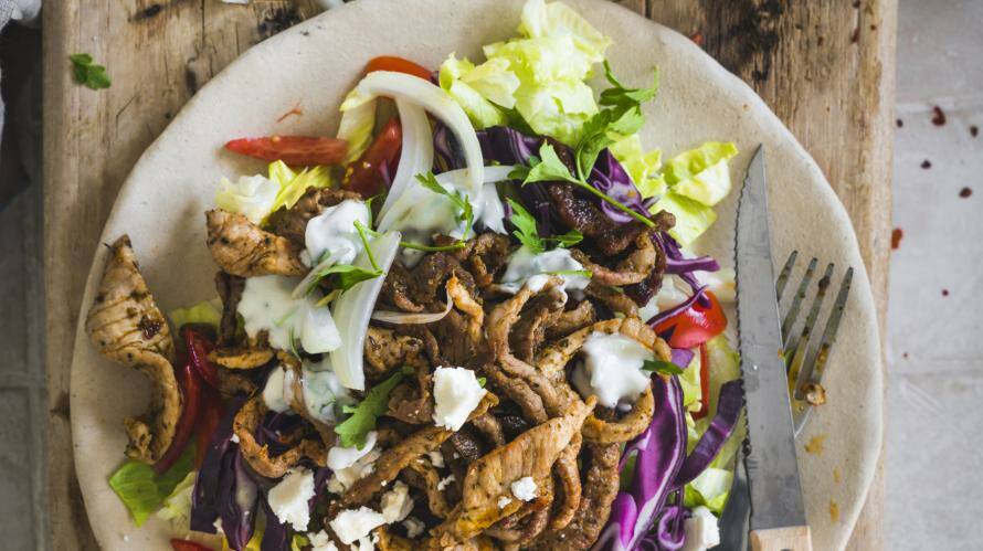 Teller mit Fleisch und Salat auf Holzbrett