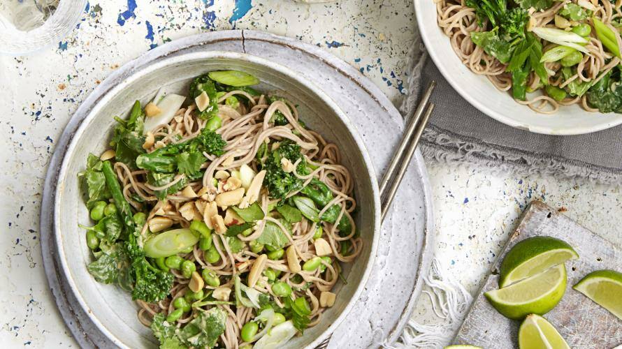 Schalen mit Asia-Nudeln, Stäbchen, Erdnüssen und Limetten