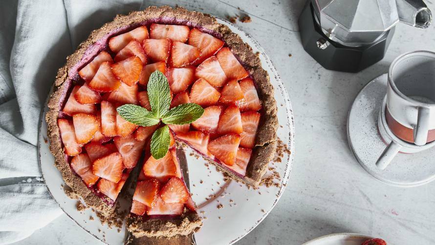 Erdbeerkuchen auf einem Teller mit Kuchenheber und Kaffeekanne