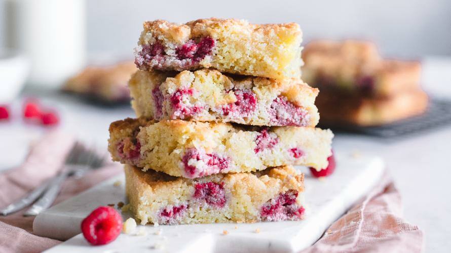 Kuchen gestapelt auf einem Brett, rosa Tuch und Kanne mit Milch