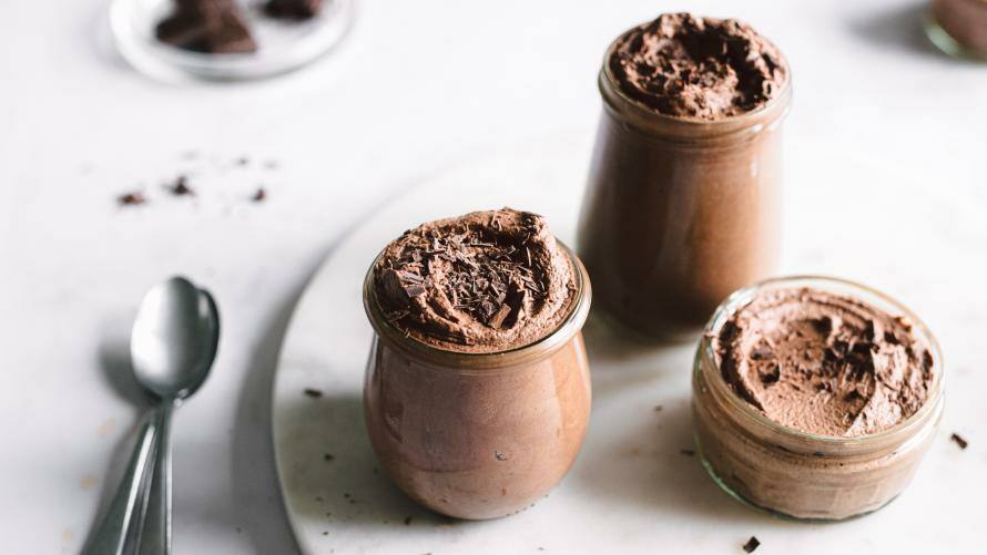 Dessert in Gläsern auf einer Platte, Löffel liegen daneben