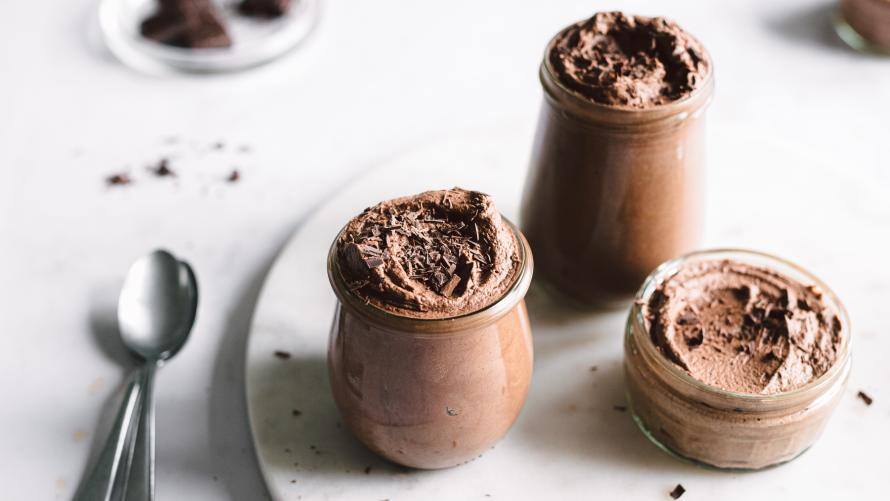 Dessert in Gläsern auf einer Platte, Löffel liegen daneben