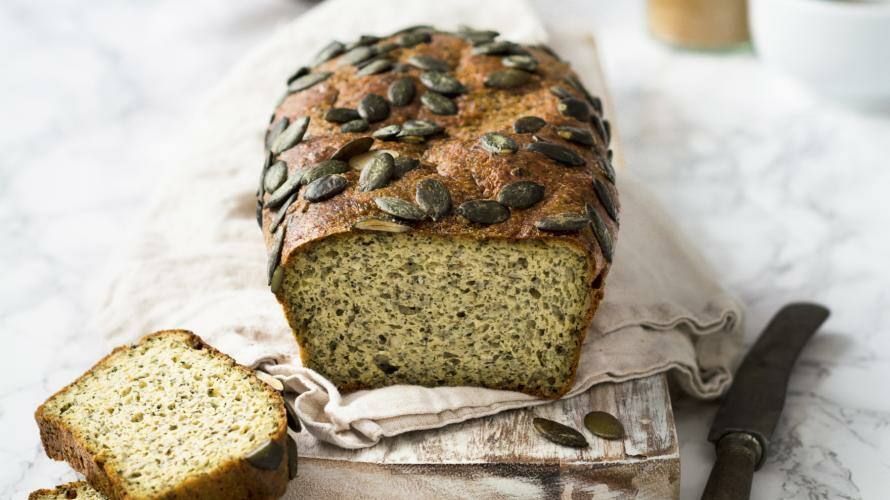 Aufgeschnittenes Kürbistoasrbrot mit Kürbiskernen auf hellem Untergrund