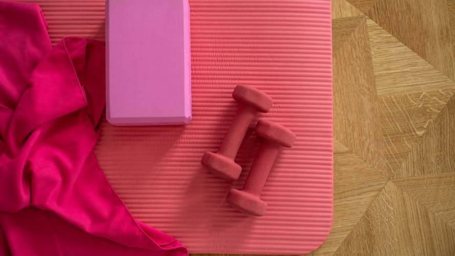 Yogablock und Gewichte auf rosaner Sportmatte