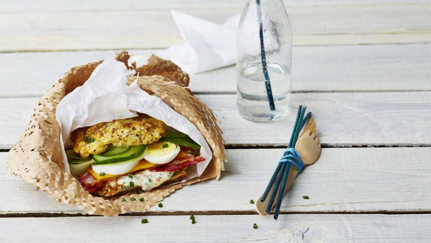 Eingepacktes Sandwich mit Bacon, Ei, Cheddar und Gurke