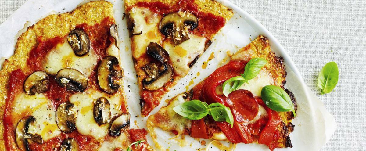 Weißer Teller mit Pizza, belegt mit Champignons, Schinken, Käse und Rucola