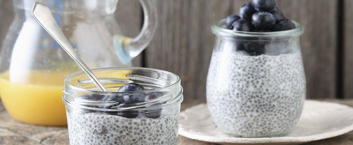 Chia-Pudding in Glas mit Beeren und Kanne mit O-Saft