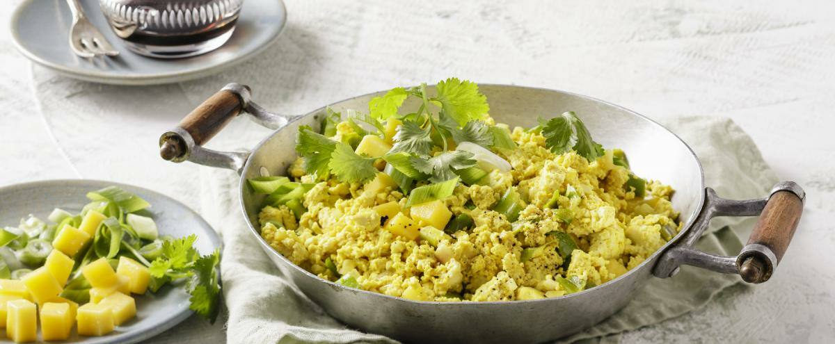 Veganes Tofu-'Rührei' mit Mango in einer schwarzen Pfanne.