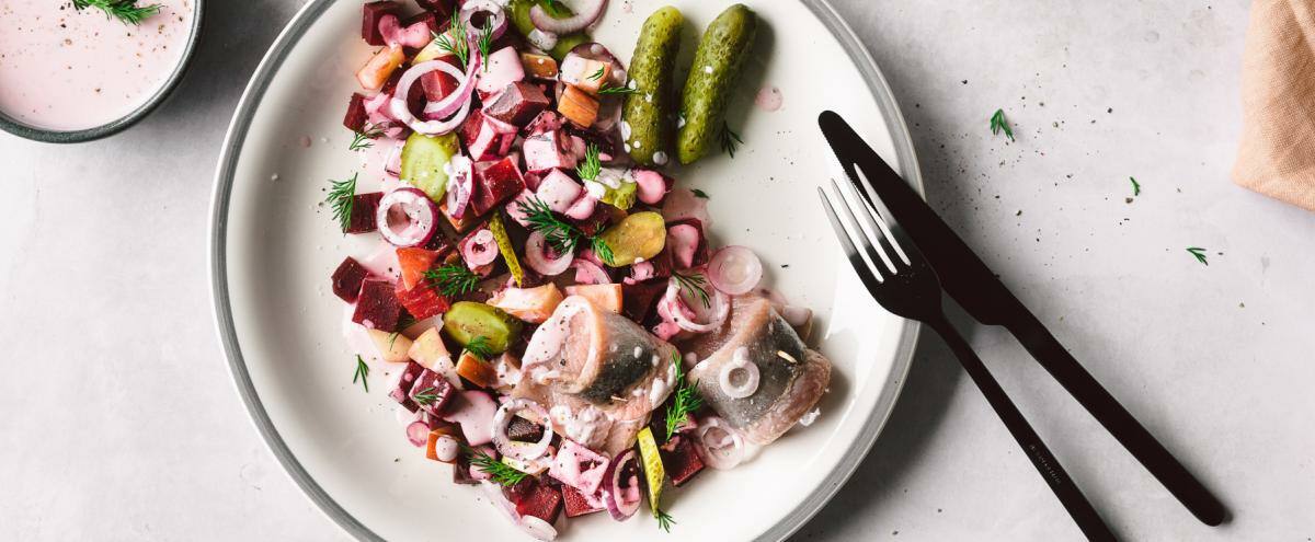 Heringssalat auf einem großen Teller mit Besteck