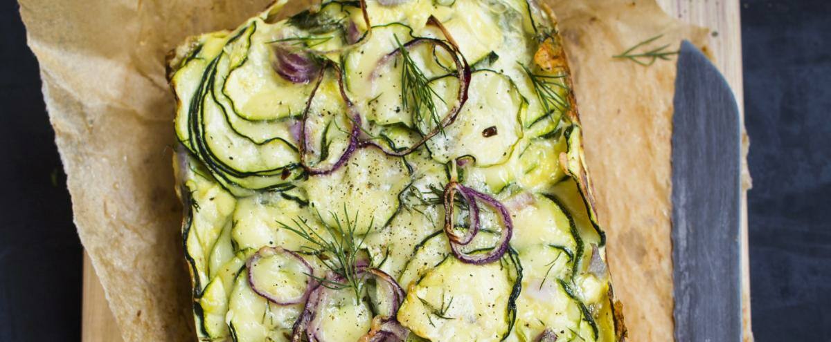 Zucchiniauflauf auf Backpapier und Brett mit Messer