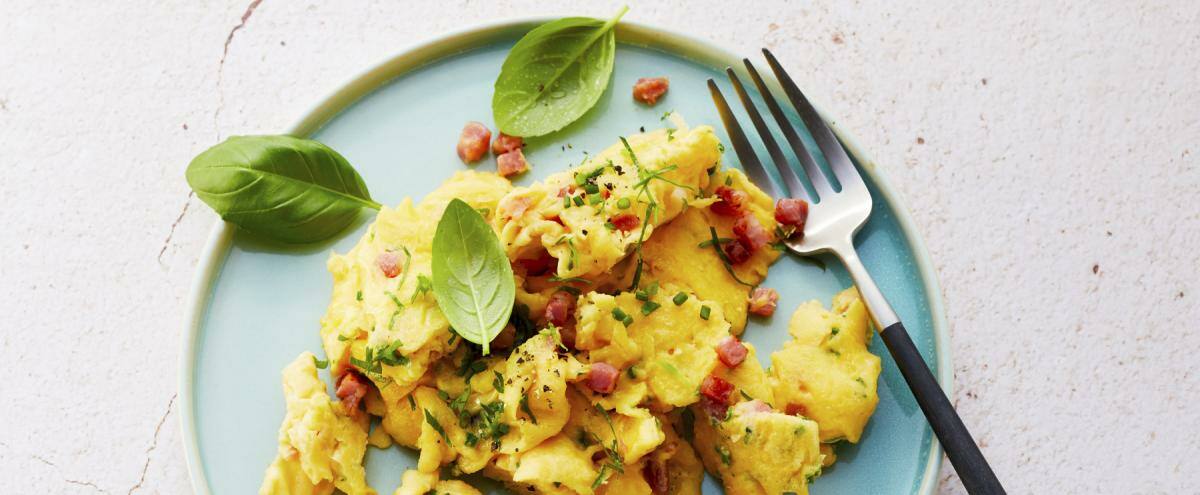 Rührei mit Speck auf einem grünen Teller mit Gabel