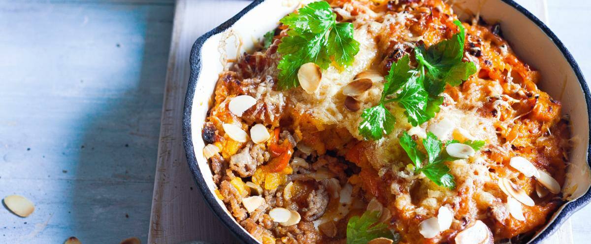 Auflauf in einer Pfanne auf Brett und Basilikum