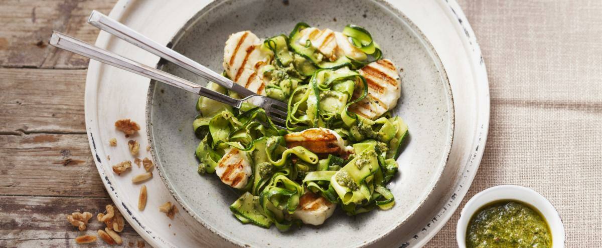 Gebratener Halloumi neben Zucchininudeln auf einem Teller