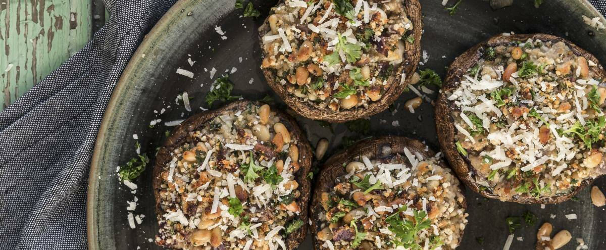 Teller mit gefüllten Pilzhüten mit Pinienkernen, Mandelmehl, Petersilie und Parmesan