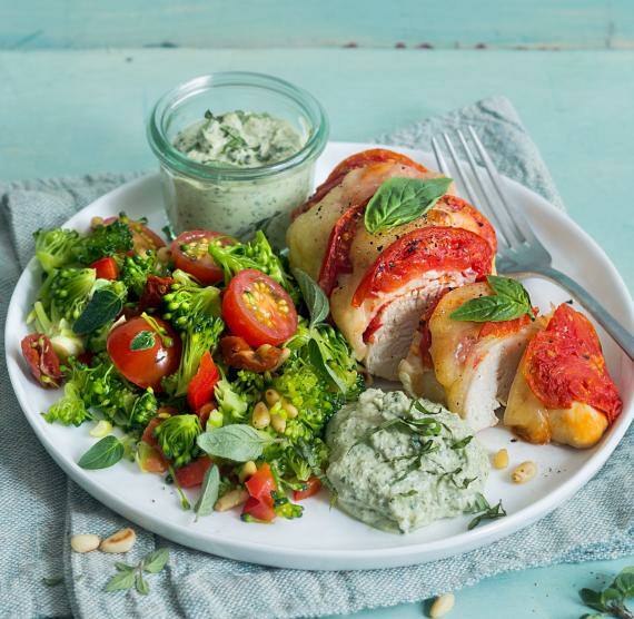 Überbackene Hähnchenteile neben Brokkoli und Dip auf einem Teller