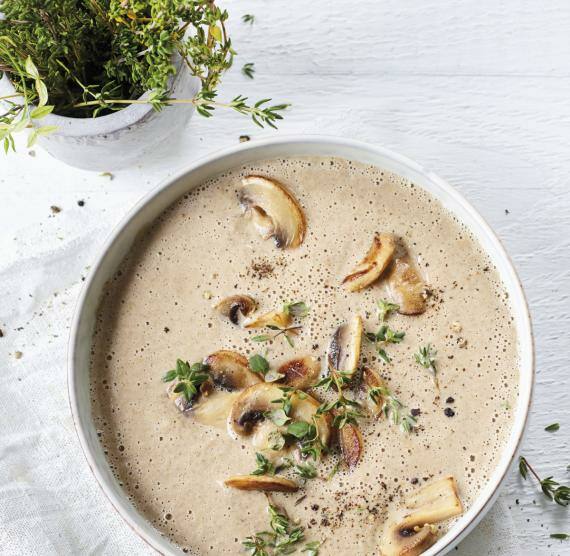 Schüssel mit hellbrauner Suppe, darin Champignons und Thymian