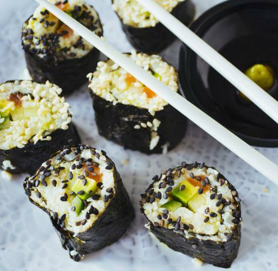 Sushi mit Blumenkohlreis auf einem Teller mit Stäbchen und Sojasauce