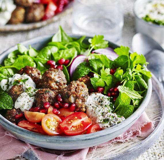 Teller mit Salat, Tomaten, Frikadellen und Joghurtsauce