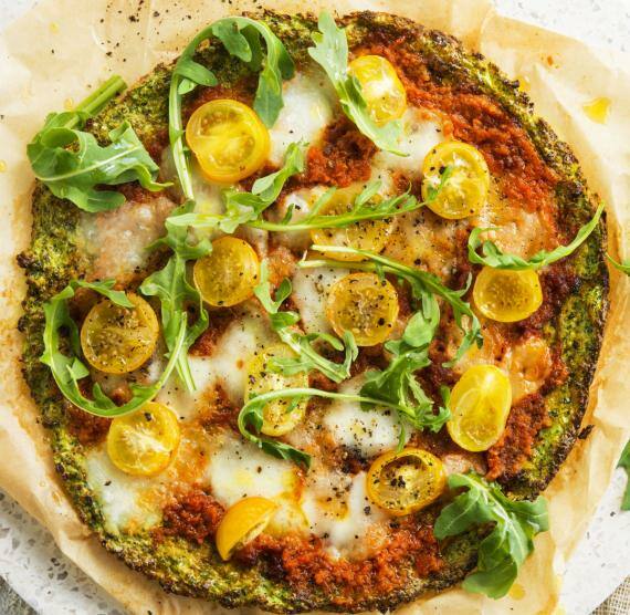 Pizza mit Tomatensauce, gelben Kirschtomaten, Mozzarella und Rucola