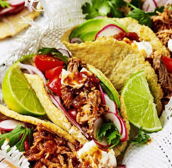 Blumenkohltortillas gefüllt mit Radieschen, Petersilie, Pulled Pork, roten Zwiebeln und Kirschtomaten, außerdem Limettenspalten