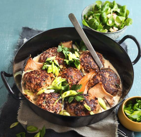 Hackbällchen mit Kräutersauce in einer schwarzen Pfanne.