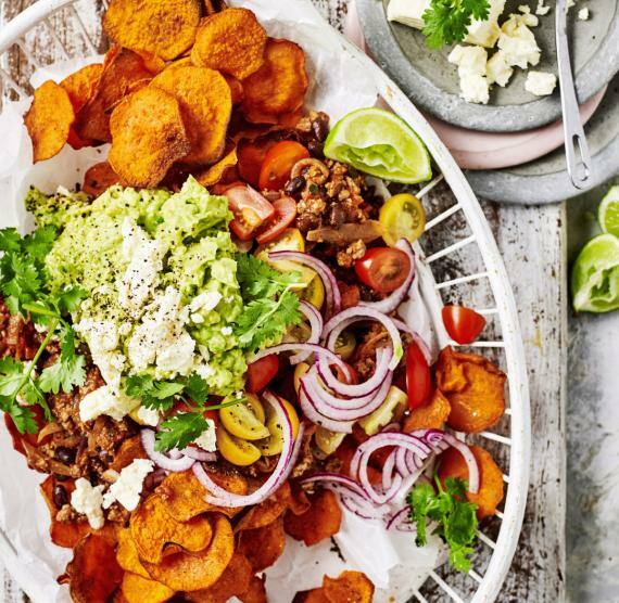 Süßkartoffel-Nachos mit Rinderhack, Avocado und Feta in einem Holzkörbchen