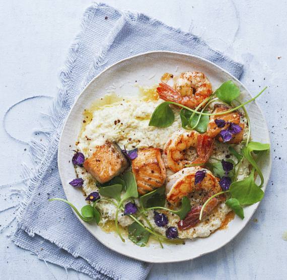 Blumenkohlreis mit Lachs und Garnelen auf einem Teller