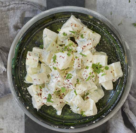 Dunkler Teller mit Kohlrabiwürfeln und Joghurt-Mayo-Dressing