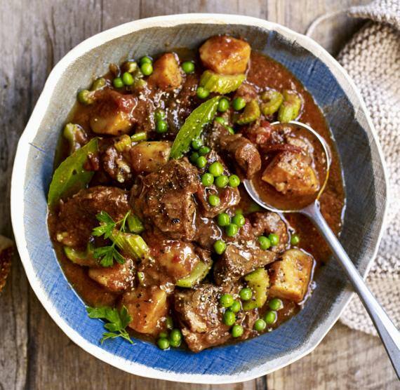 Schüssel mit Rindfleisch-Eintopf, Erbsen, Lorbeer, Kohlrabi und Petersilie