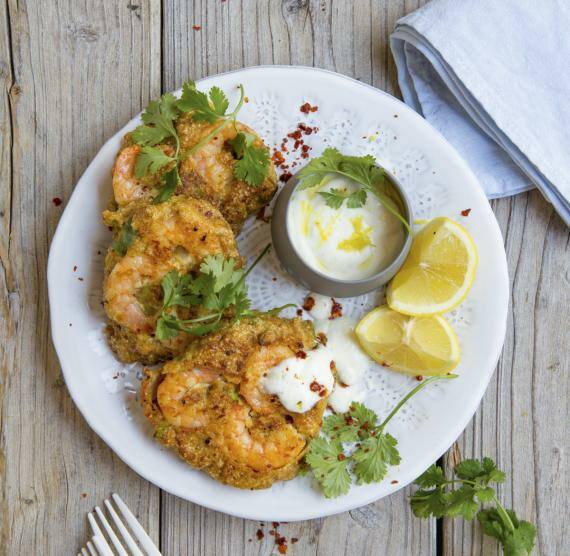 Pancakes mit Garnelen-Topping und Zitronen auf einem Teller