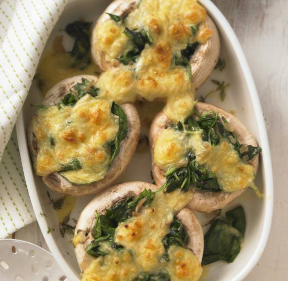 Helle Auflaufform mit 4 Riesenchampignons, gefüllt mit Spinat, überbacken mit Käse