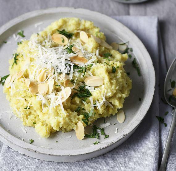 Teller mit Blumenkohlrisotto und gehobelten Mandeln, darüber Petersilie und Parmesan