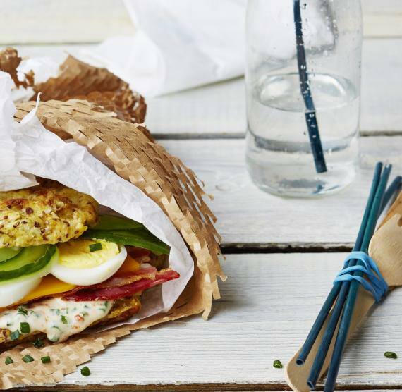 Eingepacktes Sandwich mit Bacon, Ei, Cheddar und Gurke