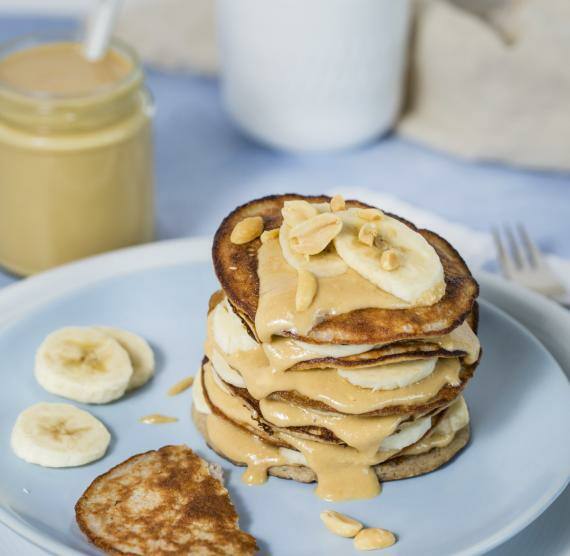 Pancakes auf Teller mit Banane und Erdnussbutter