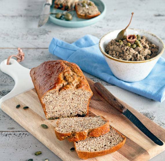 Brot auf Brett mit Messer und Aufstrich in Schale