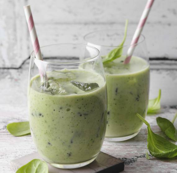 2 Gläser mit grünem Smoothie, Eiswürfeln und Strohhalm