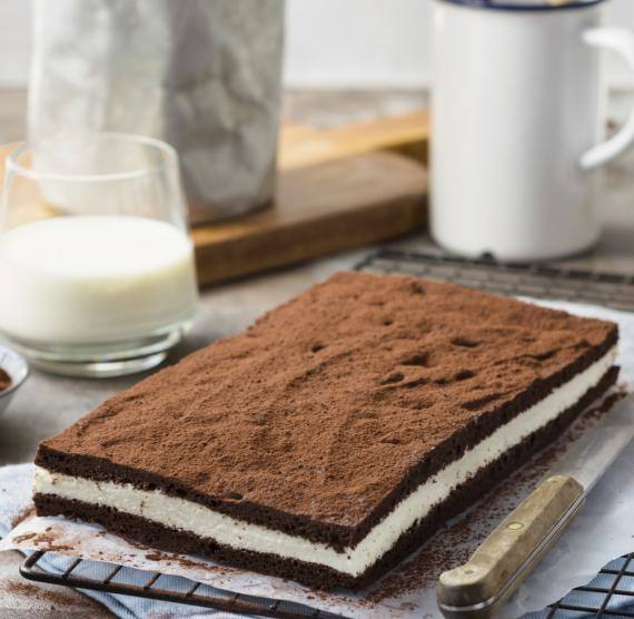 Großes Stück "Milchschnitte", daneben Glas Milch und Kakaopulver