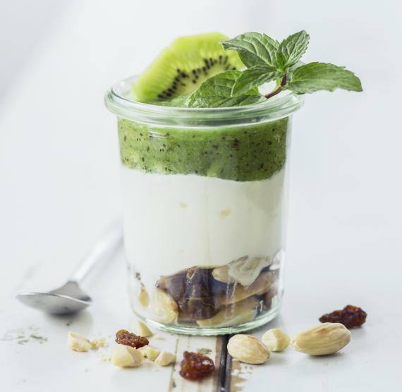 Weckglas mit drei Schichten: Mandeln, Joghurt und Kiwi-Minze