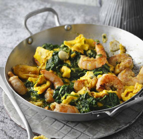 Rührei mit Spinat und Garnelen in einer Pfanne