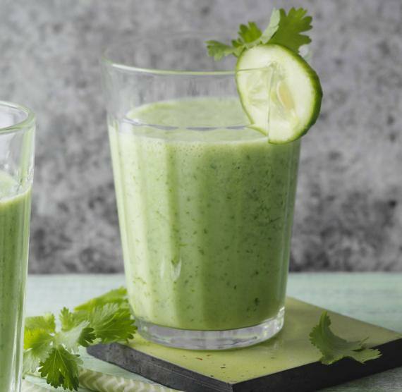 2 Gläser mit grünem Smoothie, garniert mit Gurkenscheibe und Koriandergrün
