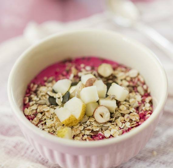 Schälchen mit pinkem Joghurt, Müsli und Beeren-Nuss-Topping